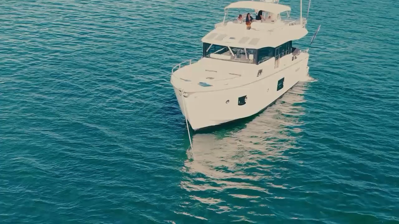 A white yacht on blue water, filmed for Summerland Yacht Sales.